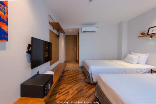 a hotel room with two beds and a flat screen tv at Mojzo Inn Boutique Hotel in Nha Trang