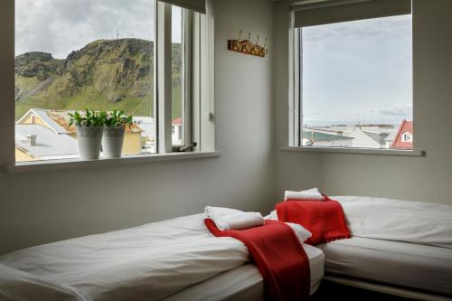 a bedroom with two beds and a window with a view at Guesthouse Sunnuhóll in Vestmannaeyjar