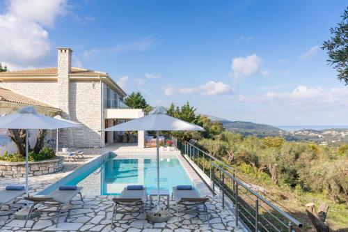 a pool with chairs and umbrellas next to a house at Villa White Stone by Rodostamo Collection in Kassiopi