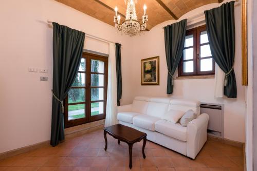 a living room with a white couch and windows at Tenuta Tegolato in Barberino di Val dʼElsa