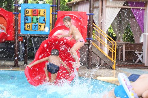 two children playing on a water slide in a pool at Hotel Majestic Mamaia Half Board & All Inclusive in Mamaia