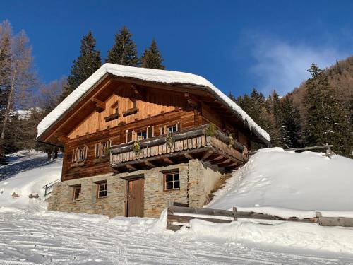 a log cabin with snow on the side of it at Ferienhof Oberer Gollmitzer in Heiligenblut