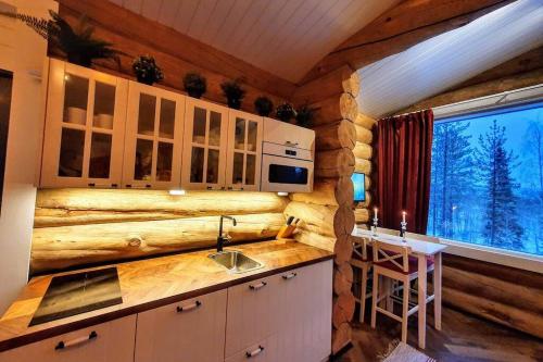 uma cozinha com um balcão com um lavatório e uma janela em Cozy Log Cabin by Invisible Forest Lodge em Rovaniemi