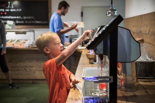 a young boy standing at a counter with his arm up at Berggasthof Hochzeigerhaus in Jerzens