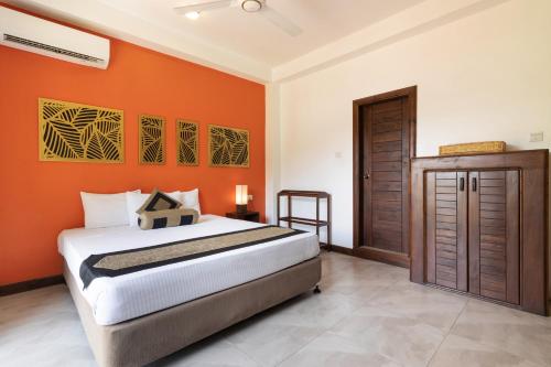 a bedroom with a bed and an orange wall at Mapakada Village - Mahiyanganaya in Mahiyangana