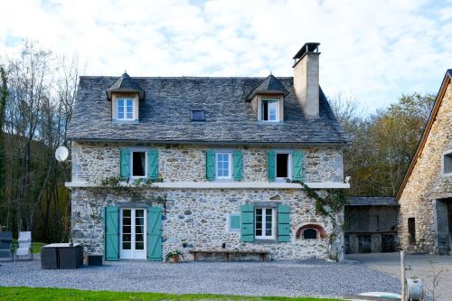 ein altes Steinhaus mit grünen Rollläden in der Unterkunft Au Nid de Caroline gîte 4 étoiles in Arette