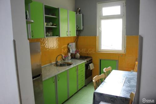 kuchnia z zielonymi szafkami, stołem i oknem w obiekcie Our house w Bordżomi