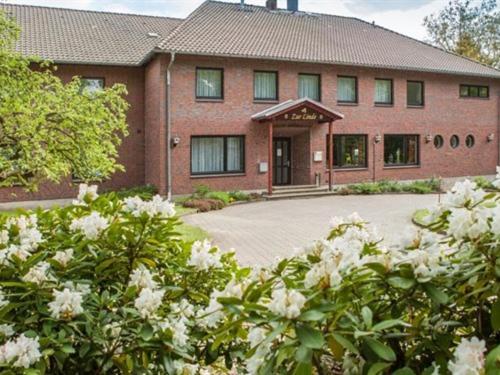 a brick building with white flowers in front of it at Hotel-Restaurant Zur Linde in Secklendorf