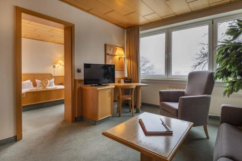 a living room with a tv and a couch and a table at Hotel Wald und See in Heringsdorf