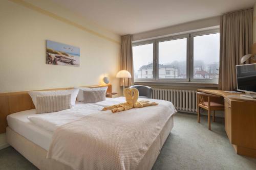 a hotel room with a bed with a stuffed animal on it at Hotel Wald und See in Heringsdorf