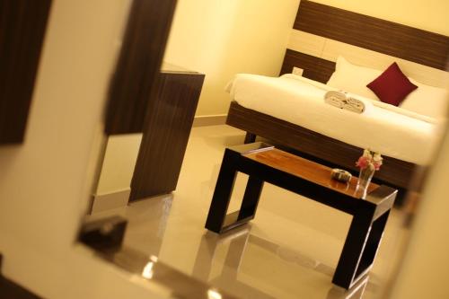a bedroom with a bed and a nightstand with a table at Sri Gnana Vedha Beach Residency in Velānganni