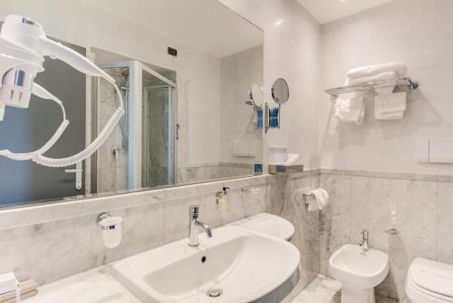 a bathroom with a sink and a toilet and a mirror at Kursaal Hotel in Cattolica