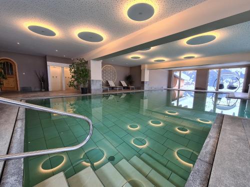 a swimming pool with a green floor in a building at Sporthotel Kalcherhof in Racines