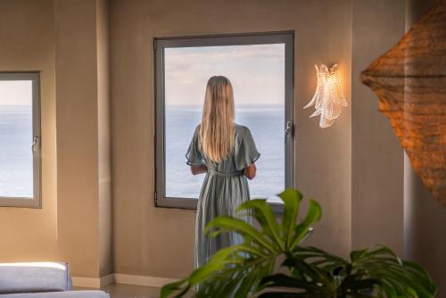 a woman looking out a window at the ocean at Okulus Madeira in Funchal