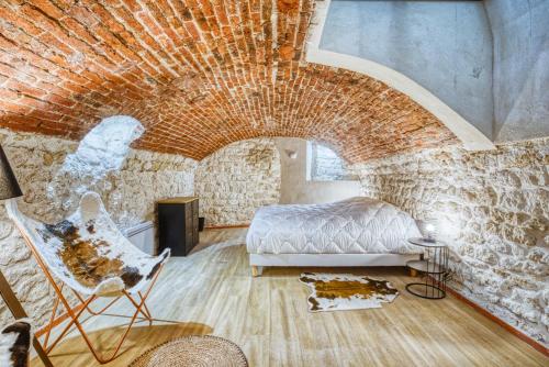 une chambre avec un lit et un mur de briques dans l'établissement Vernezza, F3 à deux pas de Montparnasse, à Paris