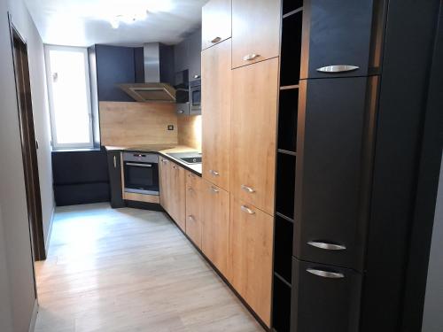a kitchen with wooden cabinets and a black refrigerator at Colmar Historic Center - LES CLEFS DE COLMAR - BookingAlsace in Colmar