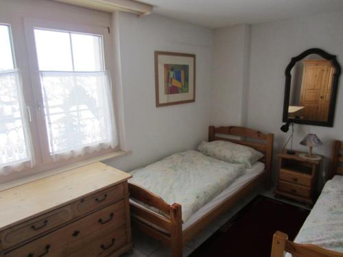 una camera con un letto e un comò e due finestre di Appartement in 1700m mit Traumblick a Grächen