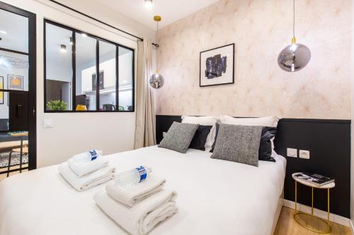 une chambre avec un lit blanc avec des serviettes dessus dans l'établissement Charming apartment - 2BR-6P - Grands Boulevards, à Paris