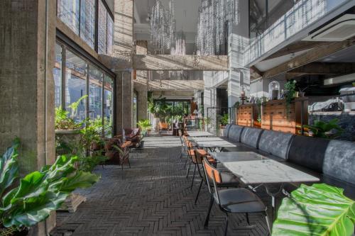 a row of tables and chairs in a building with plants at IR-ON Hotel in Bangkok