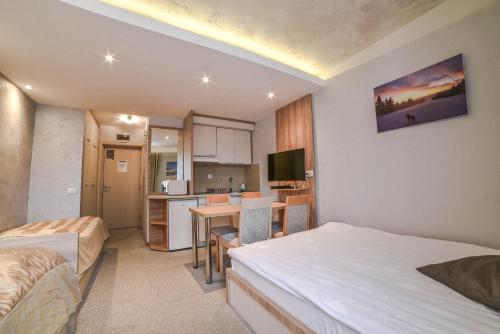 a bedroom with a bed and a kitchen with a table at Apartments Suncani Vrhovi Kopaonik in Kopaonik