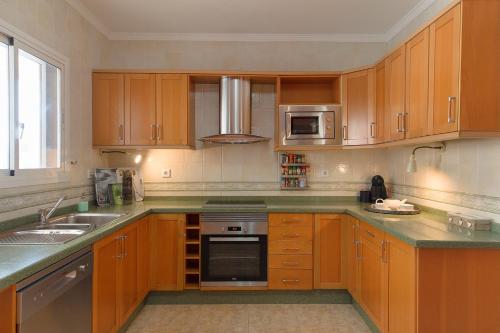 a kitchen with wooden cabinets and stainless steel appliances at Villa Golf Lanzarote in Costa Teguise