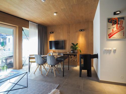 a living room with a table and chairs and a television at CHALEYOTT Mountain Apartments in Harrachov