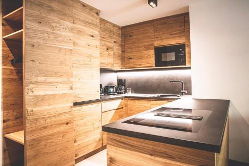 a kitchen with wooden cabinets and a black counter top at Hotel & Appartements Alpenresidenz Viktoria in Neustift im Stubaital