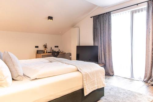a bedroom with a large bed and a large window at Hotel & Appartements Alpenresidenz Viktoria in Neustift im Stubaital