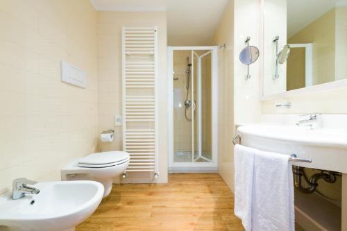 ein Bad mit einem WC, einem Waschbecken und einer Dusche in der Unterkunft Caravel Bike Hotel in Nago-Torbole