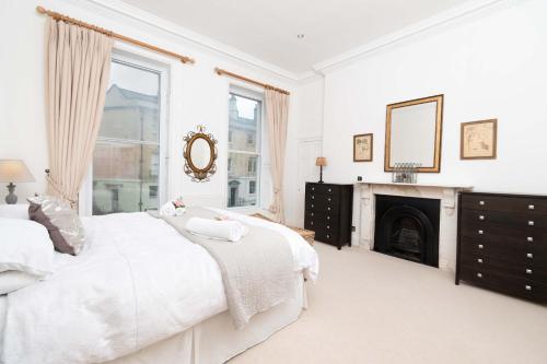 a white bedroom with a fireplace and a bed at No 1 The Paragon in Bath