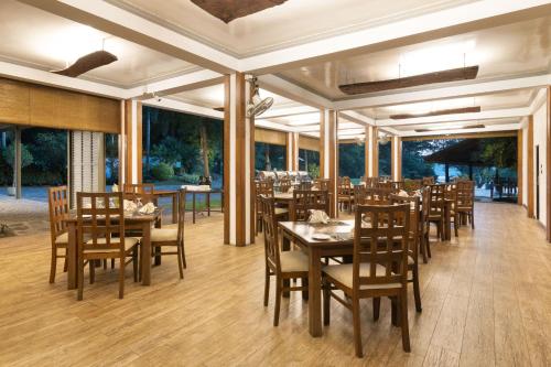 un restaurante con mesas y sillas de madera y ventanas grandes en Mapakada Village - Mahiyanganaya en Mahiyangana