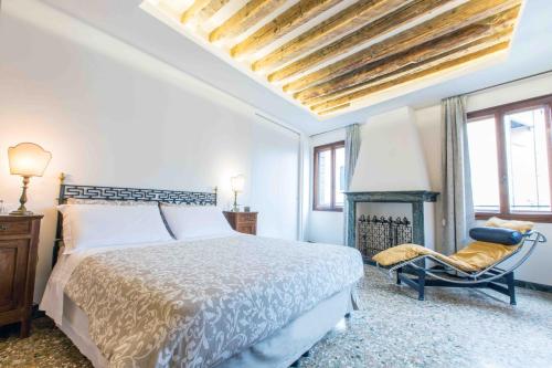 um quarto com uma cama, uma cadeira e uma lareira em CA GRIMANI Double Apartment: private terrace and stunning view em Veneza