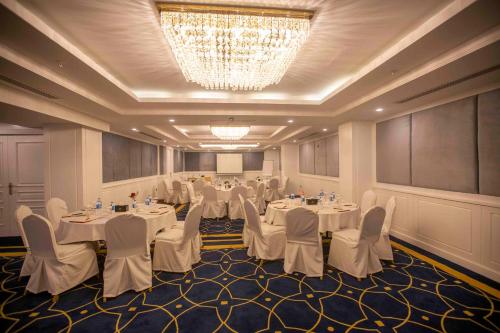 a banquet room with white tables and chairs and a chandelier at Ankawa Royal Hotel & Spa in Erbil