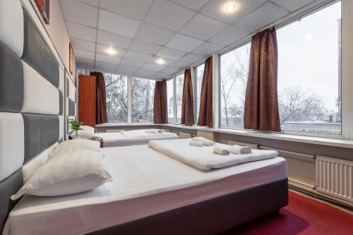 two beds in a room with large windows at Hotel Viven in Moscow