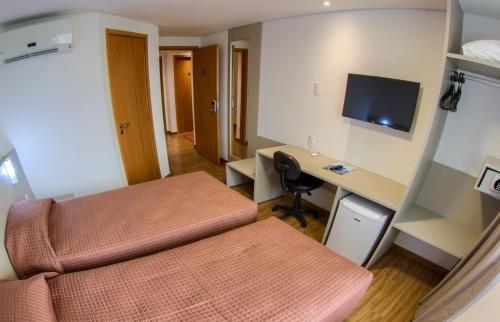 a room with a bed and a desk with a computer at Marante Executive Hotel in Recife
