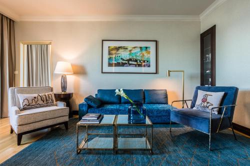 a living room with a blue couch and two chairs at InterContinental Warszawa by IHG in Warsaw