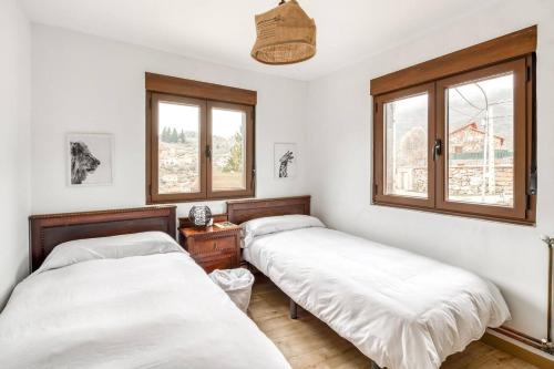 two beds in a room with two windows at Peña Moneca in Valporquero de Torío