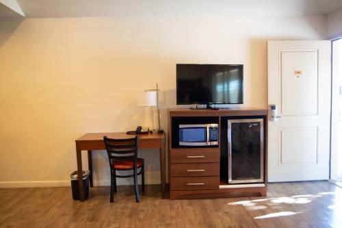 a room with a desk with a microwave and a television at Sterling Inn in Santa Clara