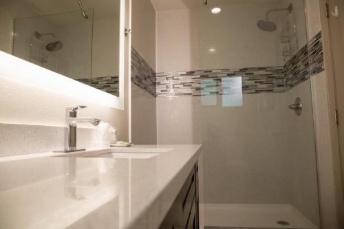 a white bathroom with a sink and a shower at Sterling Inn in Santa Clara