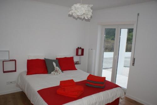 Un dormitorio con una cama con almohadas rojas. en VillaVie CostadePrata, en Alfeizerão