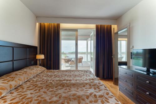 een slaapkamer met een groot bed en een televisie bij Holiday Club Naantali Apartments in Naantali