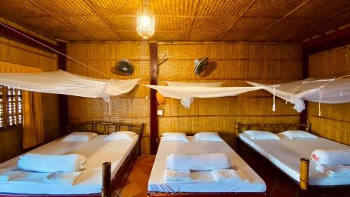 a room with four beds in a room with a ceiling at mekong riverside homestay in Vĩnh Long