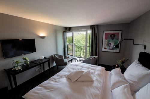 a bedroom with a white bed and a television at Prevôt Restaurant & Hotel in Cologne