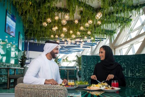 a man and a woman sitting at a table eating food at Andaz Capital Gate Abu Dhabi - a concept by Hyatt in Abu Dhabi