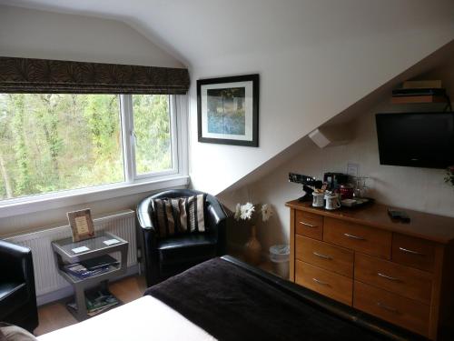 a bedroom with a bed and a tv and a chair at Glenville House - Adults Only - Incl FREE off-site health club with swimming pool, hot tub, sauna & steam room in Windermere