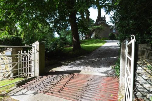 a gate to a driveway with a house in the background at The Old Rectory Bed and Breakfast in Ruthin