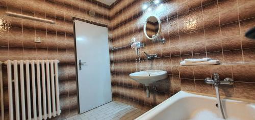 uma casa de banho com uma banheira, um lavatório e um espelho. em M-Tourist em Praga