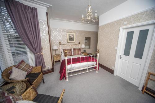 a bedroom with a bed and a chair and a window at Glenville House - Adults Only - Incl FREE off-site health club with swimming pool, hot tub, sauna & steam room in Windermere