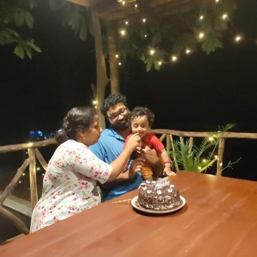 a man and a woman and a child sitting at a table with a cake at Beyond Eco Living in Munnar
