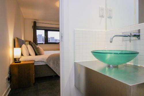 een badkamer met een wastafel en een slaapkamer met een bed bij Hydro Apartments in Glasgow